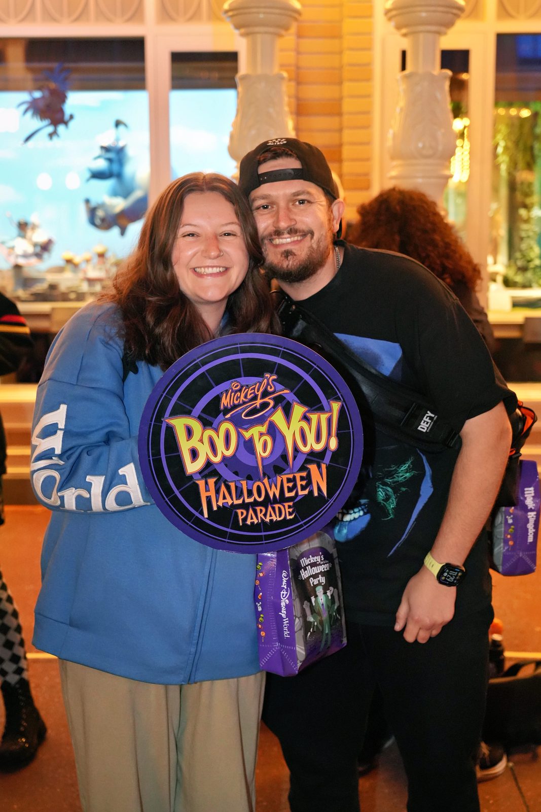Cody and his partner beside a Halloween parade sign at Walt Disney World