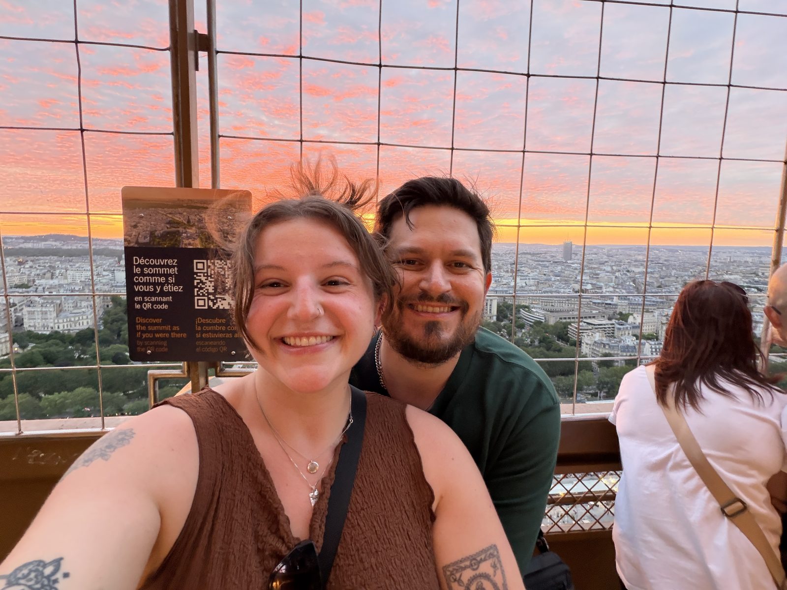 Cody and his partner at the top of the Eiffel Tower, Paris going pink behind them at sunset
