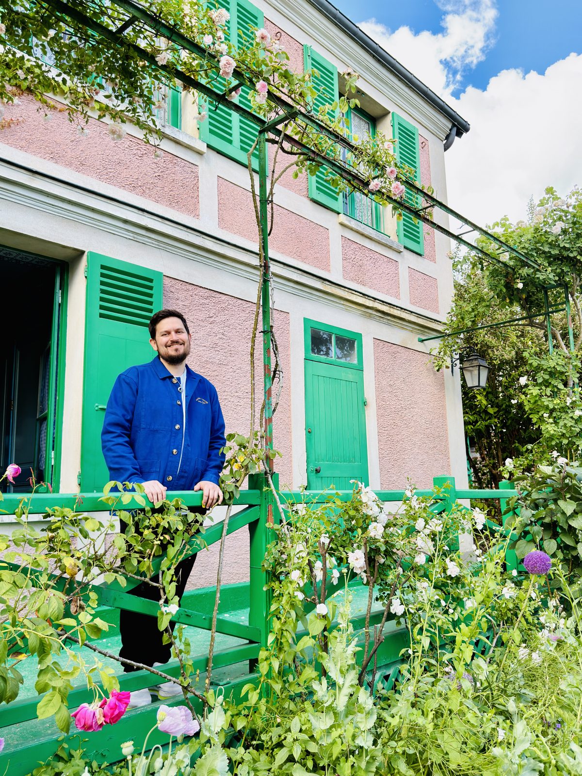 Cody on the green steps of Monet’s house at Giverny, roses on the trellis above