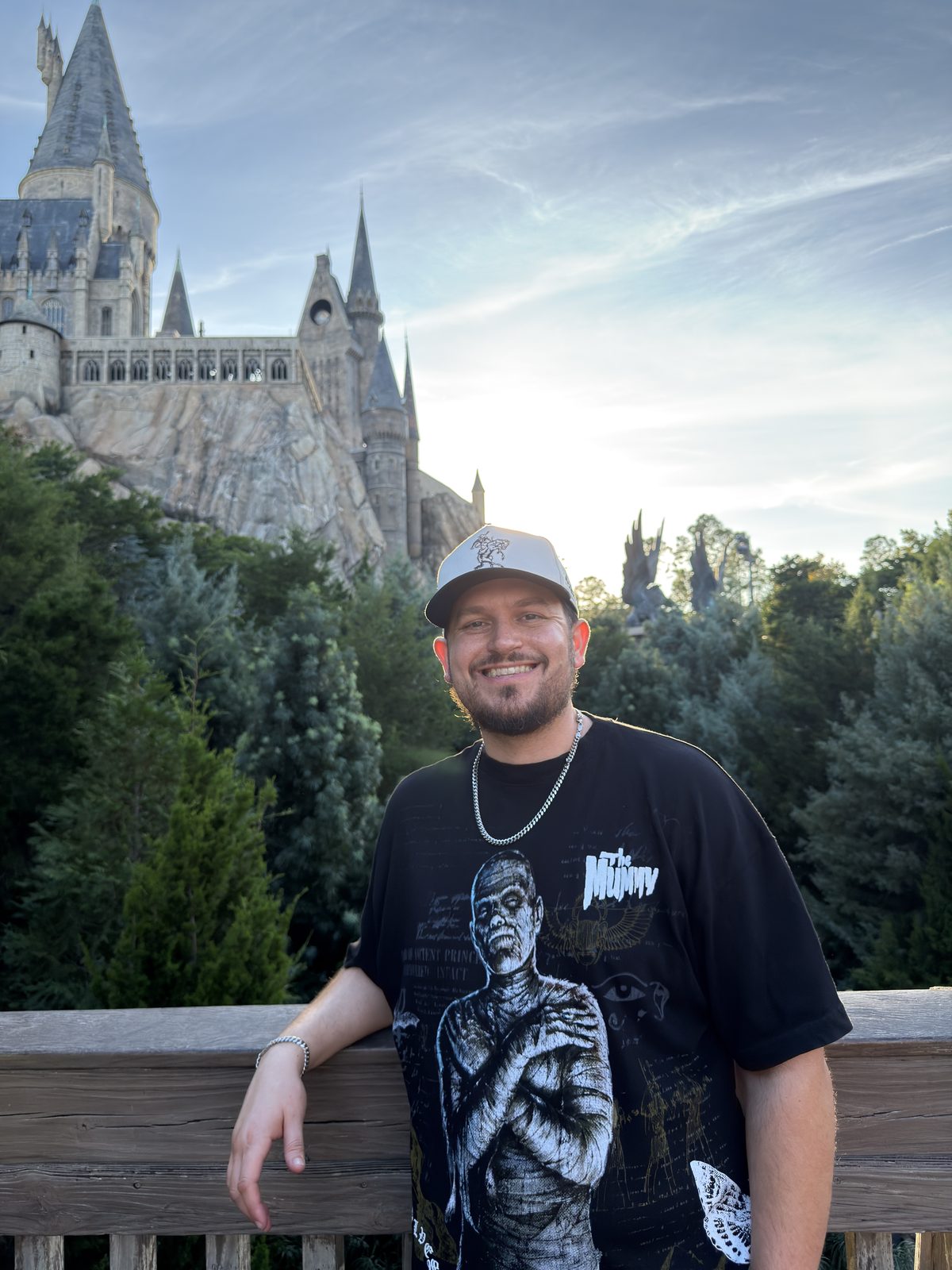 Cody at a wooden railing at golden hour, a castle on the rock behind him